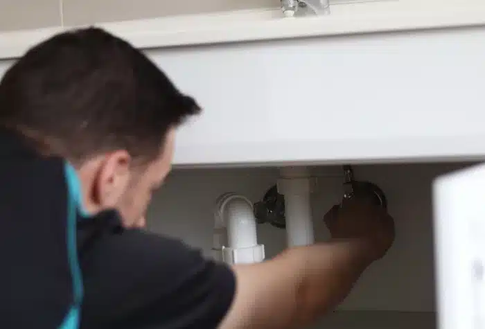 Hot water system plumbing 2 A hot water plumber turning on a hot water valve under a sink