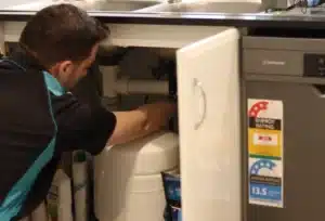 A hot water plumber installing a hot water hose and valve a sink