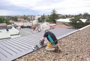 A roof plumber drilling a gutter as part of their roof plumbing services